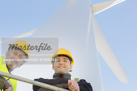 Workers standing on wind turbine in rural landscape