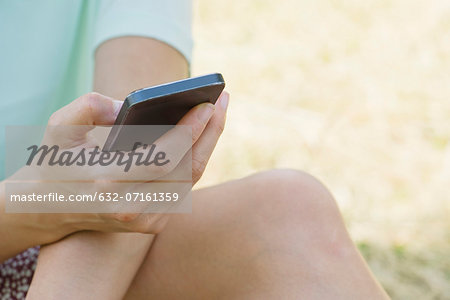 Woman using smartphone outdoors, cropped