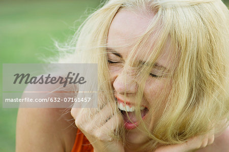 Young woman bursting out laughing with eyes closed