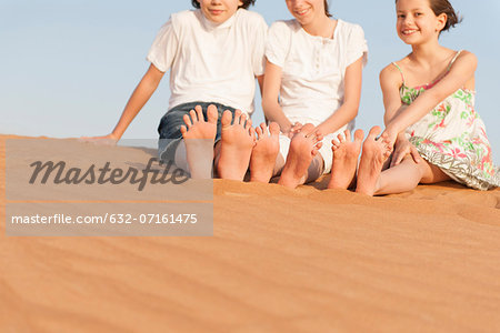 Children sitting on sand dune