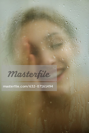 Woman behind shower door, wiping face