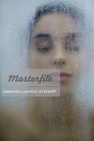 Woman behind wet glass, eyes closed, close-up