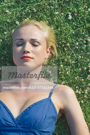 Young woman napping on grass, portrait