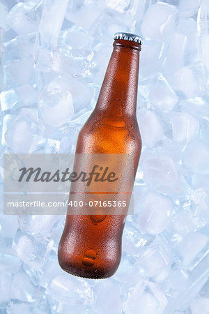 A brown bottle of beer on ice.