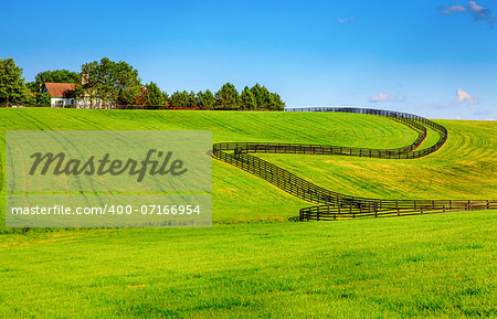 Scenic image of a horse farm with black wooden fences