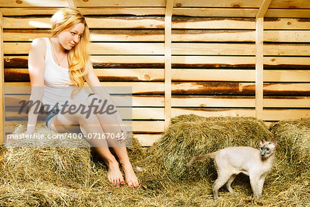 beautiful girl with cat on hayloft at summer day