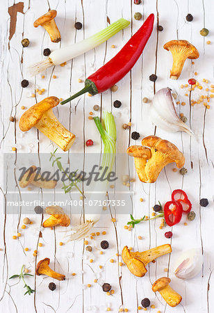 Chanterelle mushrooms and vegetables on a white wooden background.