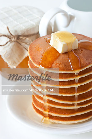 Fresh pancakes with butter and honey on a plate.