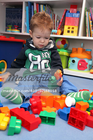 A baby boy playing with plastic blocks on the floor