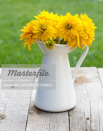 Fresh garden yellow flowers bouquet in vase on wooden table