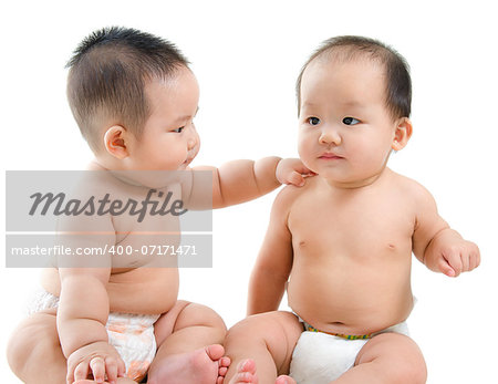 Two Asian babies having baby talk, sitting isolated over white background.
