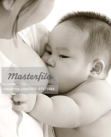 Mother and baby. Close up Asian mother breastfeeding baby boy in sepia tone.