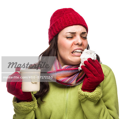 Sick Mixed Race Woman Wearing Winter Hat and Gloves Blowing Her Sore Nose and Holding Cup of Hot Tea Isolated on White.