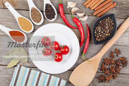 Colorful herbs and spices selection. Aromatic ingredients on wood table and cherry tomatoes on plate