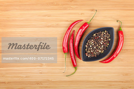 Red hot peppers and peppercorn on cutting board with copy space