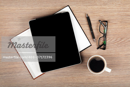 Tablet with blank screen and coffee cup on office wooden table