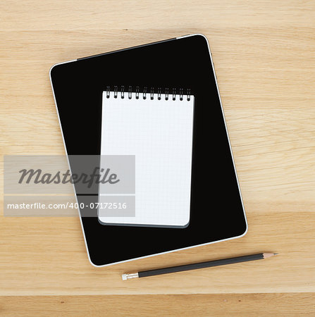 Touch screen tablet computer, notepad and pencil on wooden table