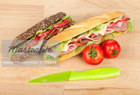 Fresh sandwiches with meat and vegetables and tomatoes on wood table