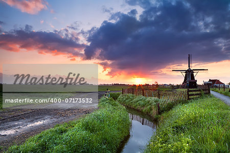 dramatic warm sunrise over Dutch windmill  and river, Groningen, Netherlands