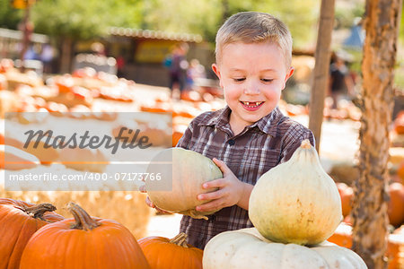 Adorable Little Boy Gathering His Pumpkins at a Pumpkin Patch on a Fall Day.