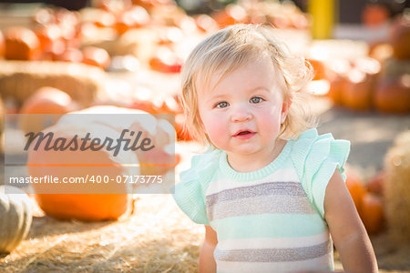 Adorable Baby Girl Having Fun in a Rustic Ranch Setting at the Pumpkin Patch.