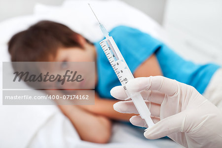 Worried child about to receive an injection or vaccine - focus on syringe