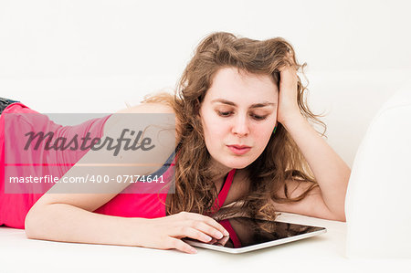 Smiling young woman on the couch with her tablet