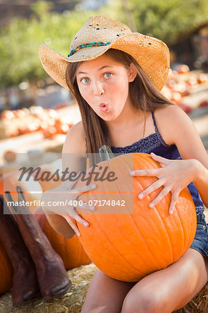 Preteen Girl Holding A Large Pumpkin at the Pumpkin Patch in a Rustic Setting.