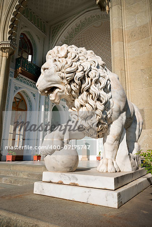 Sculpture of lion with a ball on a background of palace