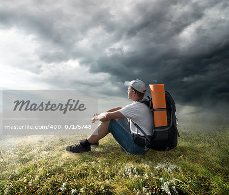 Tourist resting on the hill under storm clouds