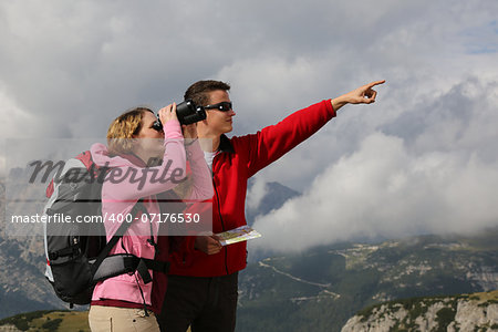 Young woman searching the destination while her boyfriend is showing the direction in the mountains