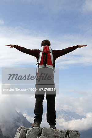 A young climber on a mountain top stretching his arms like flying