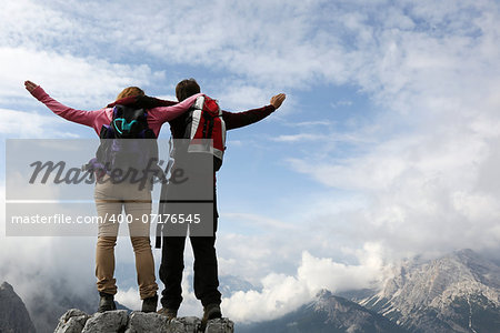 Two young mountaineers standing on mountain top and enjoying their success