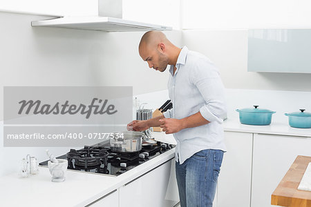 Side view of a young man preparing food in the kitchen at home