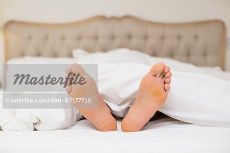 Close up of bare feet in bed at home