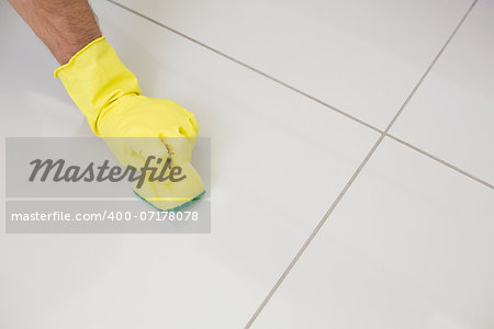 Close up of yellow gloved hand with sponge cleaning the floor at home