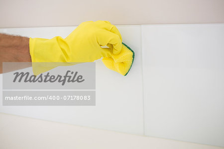 Close up of yellow gloved hand with sponge cleaning the floor at home