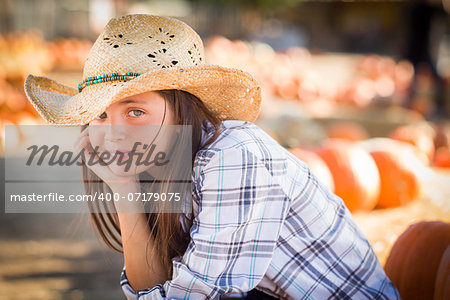 Preteen Girl Wearing Cowboy Hat Portrait at the Pumpkin Patch in a Rustic Setting.