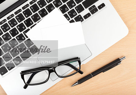 Blank business cards over laptop on wooden office table