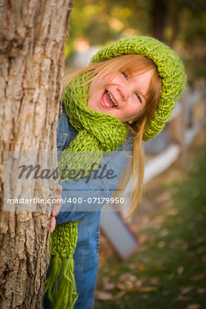 Cute Smiling Young Girl Wearing Green Scarf and Hat Posing for a Portrait Outside.