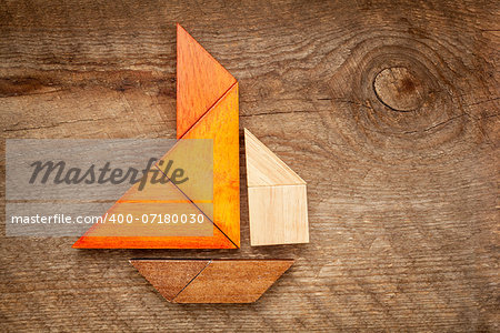 abstract picture of a sailing boat built from seven tangram wooden pieces over a rustic  barn wood, artwork created by the photographer