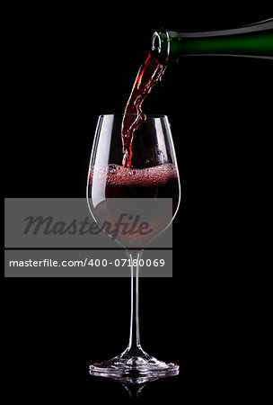 Red wine being poured into a glass on a black background