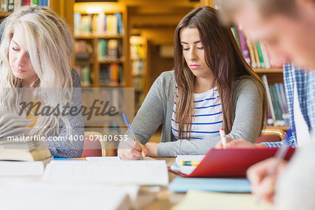 Group of students writing notes at desk in the college library