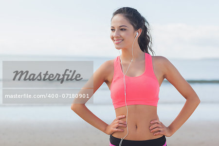 Beautiful smiling healthy woman with earphones standing on beach