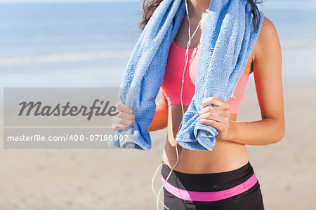 Close up mid section of a beautiful healthy woman with towel around neck standing on beach