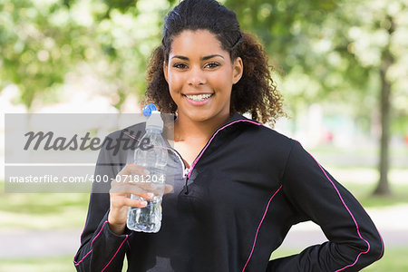 Portrait of a smiling healthy young woman with water bottle in the park