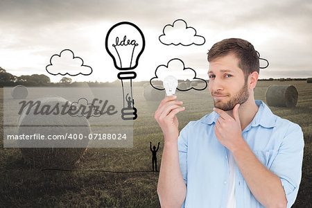 Composite image of handsome model holding a bulb