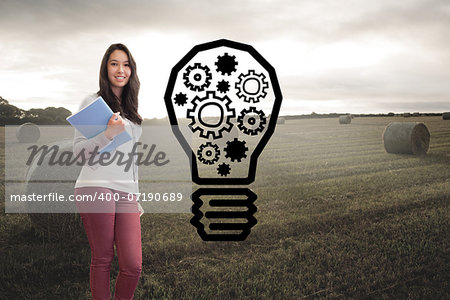 Composite image of student standing in a computer room and holding a folder while smiling