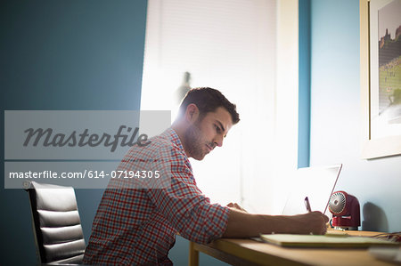 Man sitting at desk writing Man sitting at desk writing