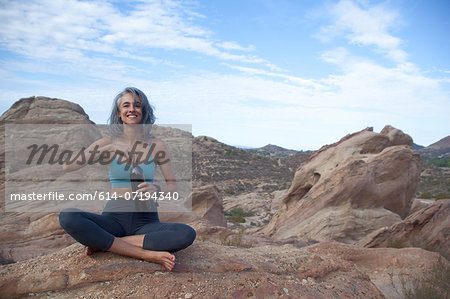 Woman sitting at Vazquez Rocks, opening drinks bottle